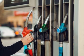 Man takes the gun on gas station, closeup view, fuel filling concept. Petrol fueling, gasoline or diesel refuel service