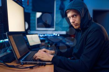 Hacker in the hood sitting at laptop, information hacking. Internet spy, male programmer trying to hack an encrypted network