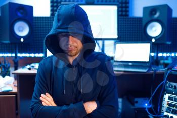 Hacker in hood at his workplace with laptop and PC, password or account hacking. Internet spy, crime lifestyle, risk job, network criminal