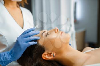 Cosmetician in gloves holds syringe with botox injection, female patient on treatment table. Rejuvenation procedure in beautician salon. Doctor and woman, cosmetic surgery against wrinkles