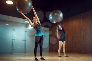 Two women in sportswear, pilates training with balls in gym. Fitness workuot in sport club. Athletic female person, aerobics indoor, body stretching
