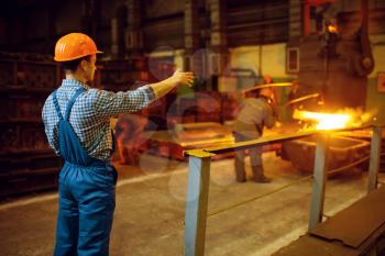 Master looks on steelmaking process in furnace, steel factory, metallurgical or metalworking industry, industrial manufacturing of metal production on mill