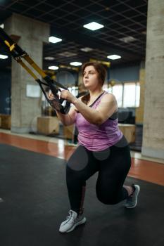 Overweight woman doing stretching exercise in gym, active training. Obese female person struggles with excess weight, aerobic workout against obesity, sport club