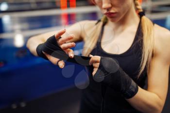 Woman winds up black bandages before boxing training. Female boxer in gym, girl kickboxer in sport club, punches practice, arms care