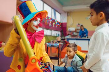 Funny clown with joyful children play in the alphabet on board. Birthday party celebrating in playroom, baby holiday in playground. Childhood happiness, childish leisure