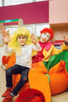 Funny clown with little boy in kindergarten. Birthday celebrating in playroom, baby holiday in playground. Childhood happiness, childish leisure