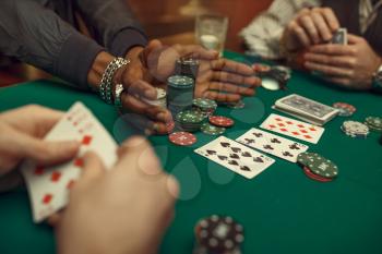 Poker players hands with cards, gaming table with green cloth on background, casino. Games of chance addiction, risk, gambling house. Men leisures with whiskey and cigars