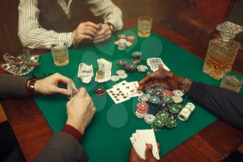 Male poker players at gaming table with green cloth, casino. Games of chance addiction, risk, gambling house. Men leisures with whiskey and cigars