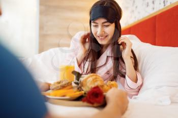 Romantic love couple, breakfast and rose in bed at home, good morning, caring husband. Harmonious relationship in young family. Man and woman resting together in their house, carefree weekend