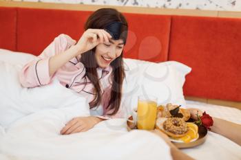 Romantic love couple, happy wife having breakfast with rose in bed at home, good morning, caring husband. Harmonious relationship in family. Woman resting in bedroom, carefree weekend