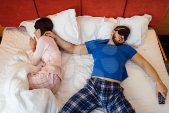 Wife is lying on the edge of the bed, sprawled husband, bad relationship. Couple having a problems, family quarrel, conflict of married man and woman