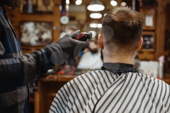 Barber in hat cuts the client 's hair. Professional barbershop is a trendy occupation. Male hairdresser and customer in retro style hair salon