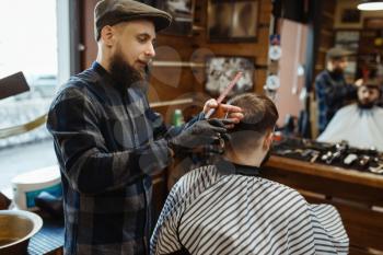 Barber makes a haircut to a client. Professional barbershop is a trendy occupation. Male hairdresser and customer in retro style hair salon