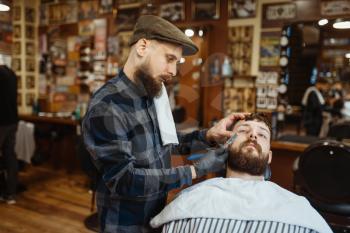 Barber with razor, old school beard cutting. Professional barbershop is a trendy occupation. Male hairdresser and client in hair salon