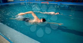 Male and female swimmers swims in the pool. Man and woman in the water, sport swimming skill training, motion view, workout before competition