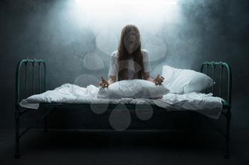 Psycho woman screams in bed, insomnia horror, dark smoky room on background. Psychedelic person having problems every night, depression and stress, sadness, psychiatry hospital