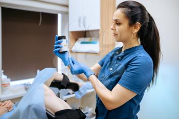Female gynecologist in gloves and uniform looking on tester. Gynecological examination in clinic, gynecology diagnostic or consultation, doctor and patient in hospital