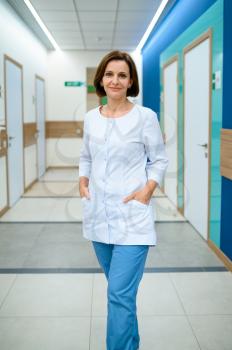 Female doctor in uniform standing in clinic corridor. Professional medical specialist in hospital, laryngologist or otolaryngologist, gynecologist or mammologist