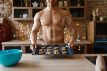 Nude man cooking pastry on the kitchen. Naked male person preparing breakfast at home, food preparation without clothes