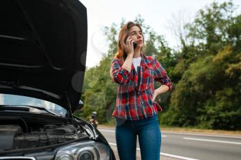 Young woman calling a tow truck on road, car breakdown. Broken automobile or emergency accident with vehicle, trouble with engine on highway