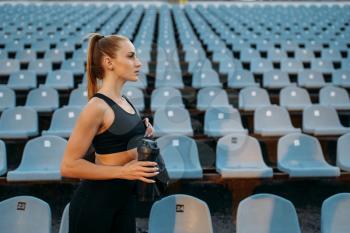 Female runner in sportswear on tribune, training on stadium. Woman doing stretching exercise before running on outdoor arena