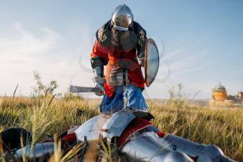 Medieval knight in armor and helmets put his sword to his opponent's throat. Armored ancient warrior in armour posing in the field