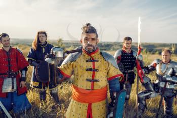 Medieval knights with swords poses in armor, great tournament. Armored ancient warriors in armour posing in the field