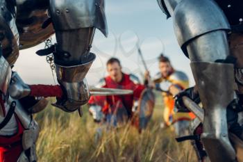 Medieval knights in armor standing opposite each other before battle. Armored ancient warrior in armour posing in the field