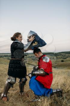 Woman wears a helmet to medieval knight, great tournament. Armored ancient warrior in armour posing in the field