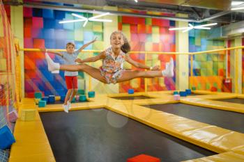 Little girl and boy having fun on kids trampoline, playground in entertainment center. Play area for children indoors, playroom