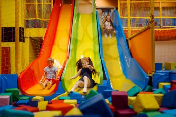Little children having fun on inflatable slide, playground in entertainment center. Play area indoors, playroom