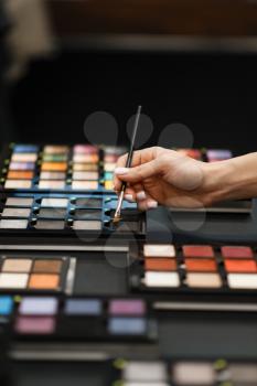 Woman with brush choosing eye shadows tone in cosmetics store. Buyer in luxury beauty shop salon, female customer in fashion market