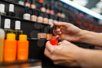 Woman choosing nail varnish color in cosmetics store. Buyer in luxury beauty shop salon, female customer in fashion market