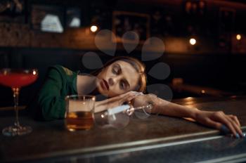 Drunk young woman sleeping at the counter in bar. One female person in pub, human emotions, leisure activities, nightlife