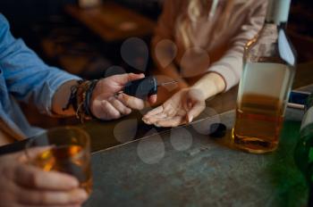 Drunk man gives the car keys to his sober woman at the counter in bar. Male person resting in pub, leisure activities. A reasonable act, refuses to drive under the influence of alcohol