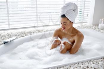 Sexy woman relax in the bath with foam. Female person in bathtub, beauty and health care in spa, wellness treathment in bathroom, pebbles and candles on background