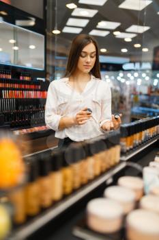 Attractive woman at the shelf in cosmetics store. Buyer at the showcase in luxury beauty shop salon, female customer in fashion market