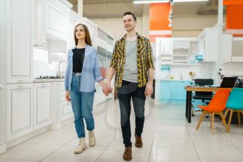 Young love couple in furniture store showroom. Man and woman looking assortment in shop, husband and wife buys goods for modern home interior