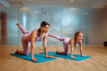 Mother and daughter doing stretching exercise on mats in gym, pilates workout. Mom and little girl in sportswear, joint training in sport club