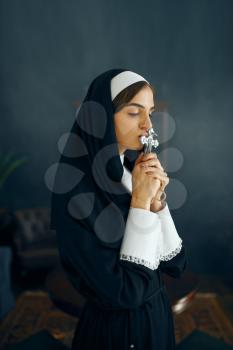 Young nun in a cassock prays crossed her arms. The sister in the monastery, religion and faith