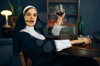 Sexy nun in a cassock smokes cigare and drinks wine, vicious desires. Corrupt sister in the monastery, religion and faith, sinful religious people, attractive sinner