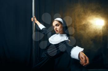Sexy perverse nun in a cassock dances on a pole like a stripper, vicious desires. Corrupt sister in the monastery, sinful religious people, attractive sinner