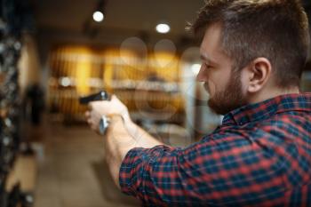 Man aims with new handgun in gun shop. Male person buying pistol for security in weapon store, selfdefence and sport shooting hobby