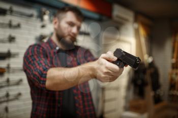 Man aims with two handguns in gun shop. Male person buying pistol for security in weapon store, selfdefence and sport shooting hobby