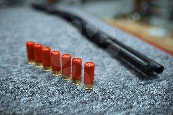 Rifle and row of ammo in gun shop, closeup, nobody. Euqipment for hunters on stand in weapon store, hunting and sport shooting hobby