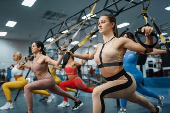 Group of attractive women doing exercise in gym. People on fitness workout in sport club, athletic girls in sportswear on training indoors