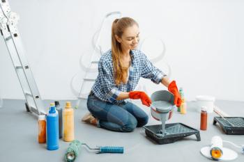 Female house painter prepares for work. Home repair, laughing woman doing appartment renovation, room decoration renovating