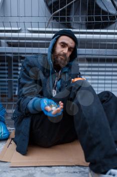 Bearded dirty poor begging on city street. Poverty is a social problem, homelessness and loneliness, alcoholism and drunk addiction, urban lonely