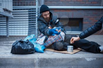 Male bearded beggar begging on city street. Poverty is a social problem, homelessness and loneliness, alcoholism and drunk addiction, urban lonely
