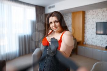 Overweight depraved woman in black and red erotic lingerie. Sexy overweight girl with big breast, corrupt large size lady